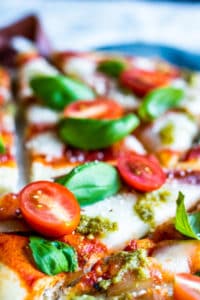 Close up of marghrerita pizza cover in tomatoes and basil.