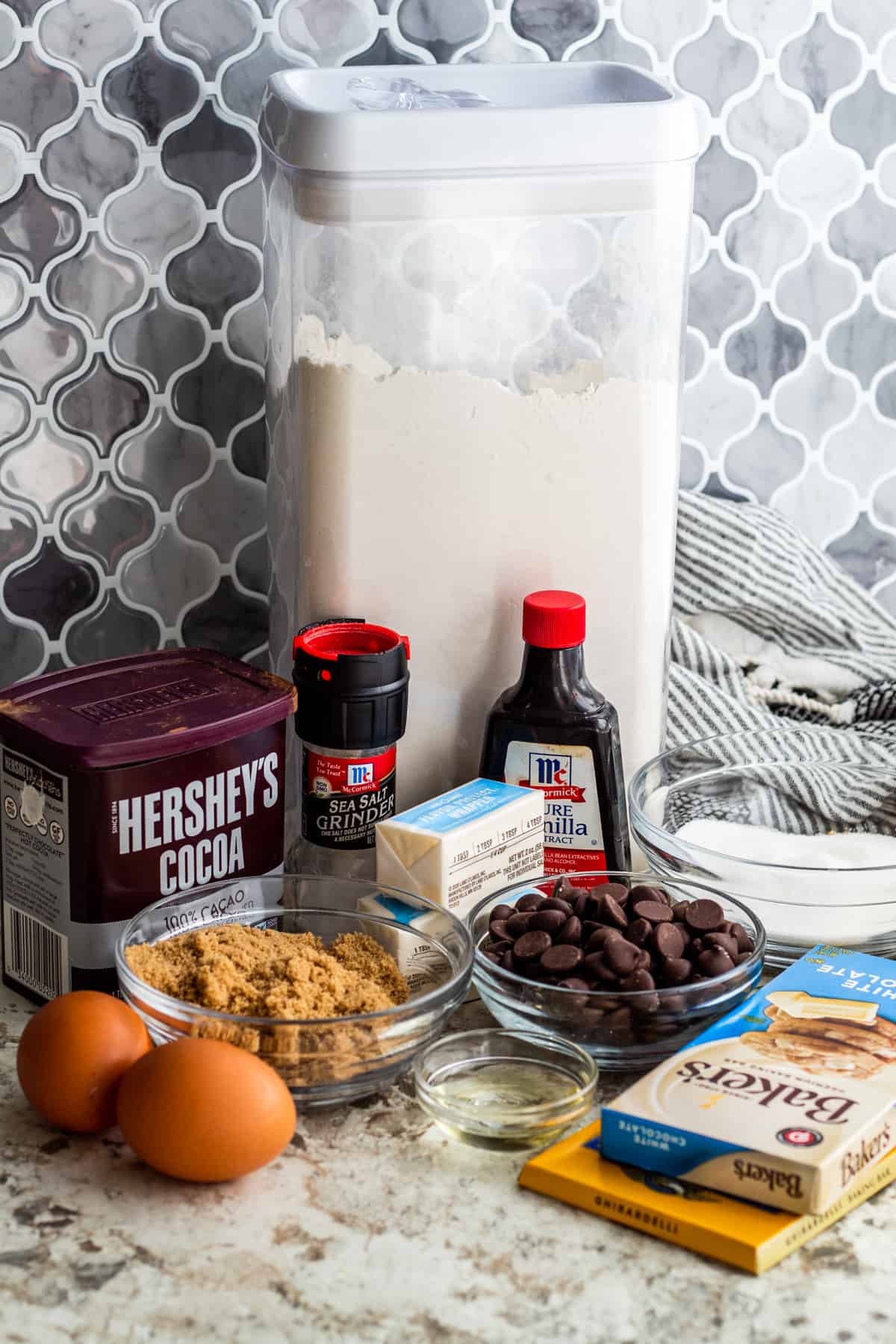 Brownie ingredients laid out on white counter in containers and small bowls.