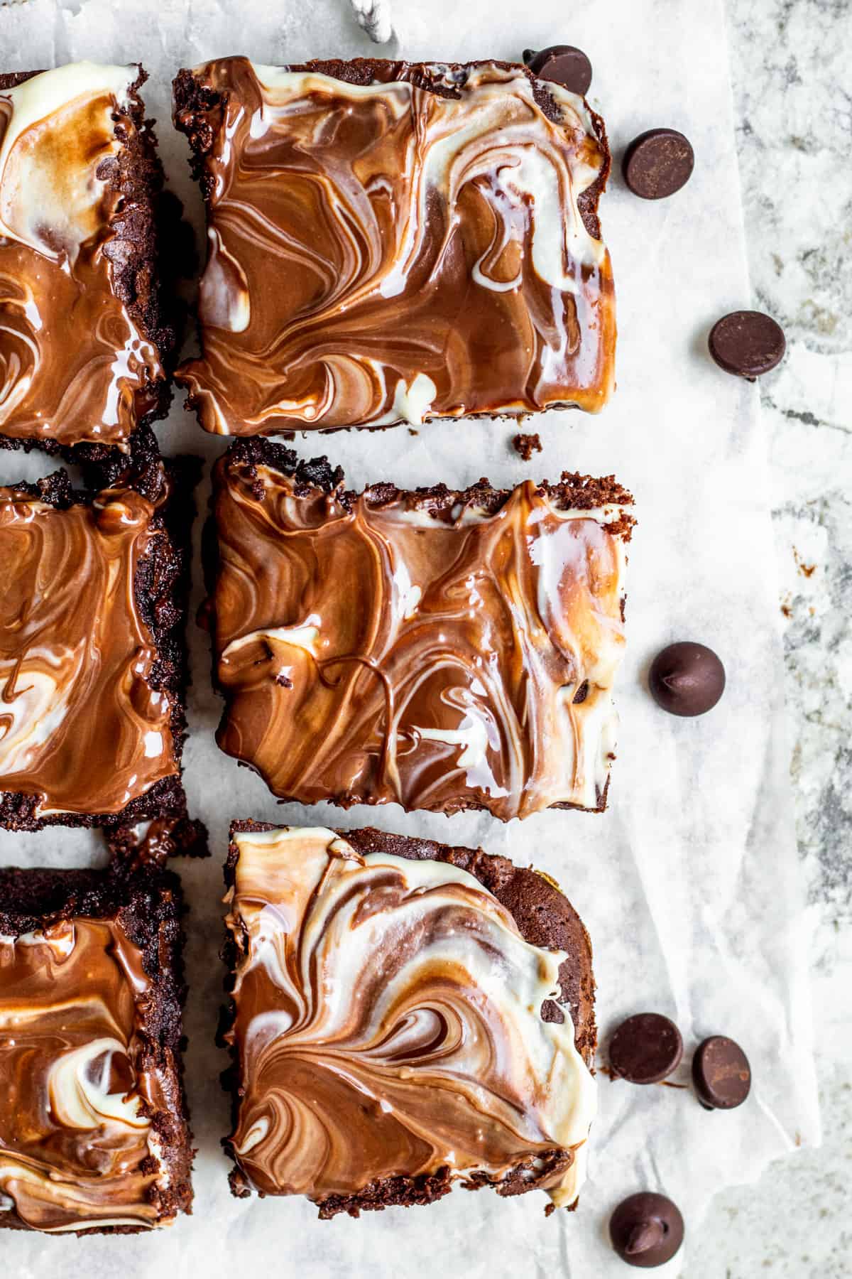 Overhead shot of brownies sliced on white parchment paper.