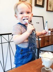 This is a photo of my son eating yogurt at the table. He is making a mess and have yogurt all over his face. This is for a article called "What Theo Eats".