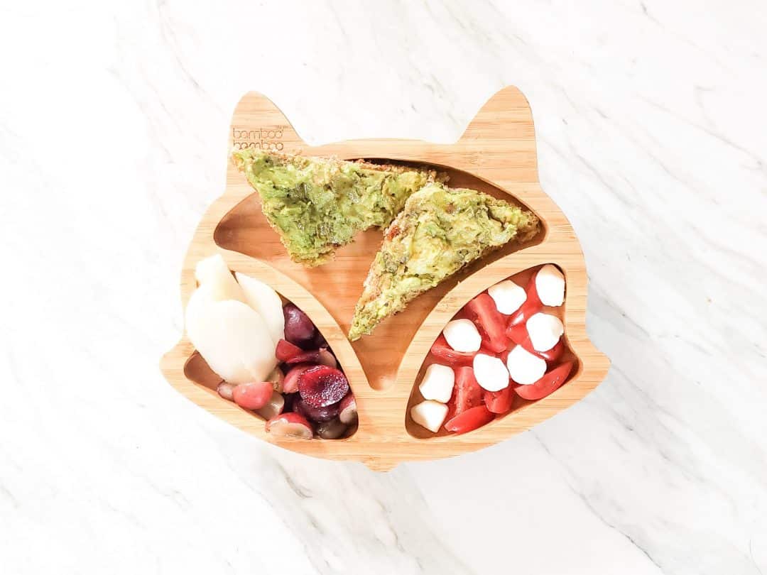 Avocado Toast BLW meal ideas. This photo is a fox plate on a marble table with my son's lunch in it. The lunch has cherries, grapes, pear, mozzarella cheese, tomatoes, and avocado on toast.