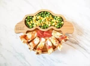 Naan pizza sticks with peas and corn on a bamboo bamboo sheep plate.