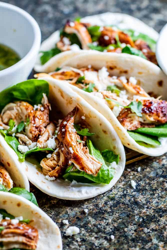 Tacos lined up on a stone counter.