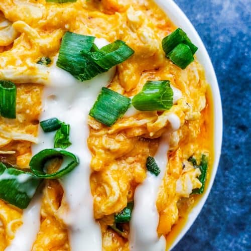 Overhead close up shot of baked buffalo chicken dip in a white bowl.