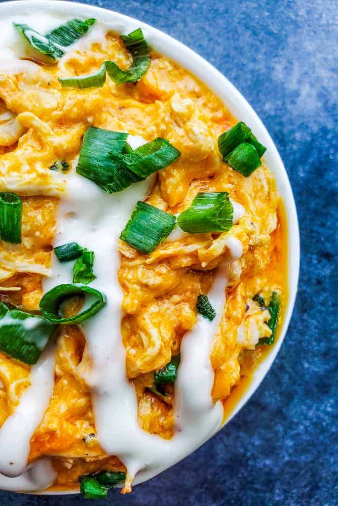 Overhead close up shot of baked buffalo chicken dip in a white bowl.