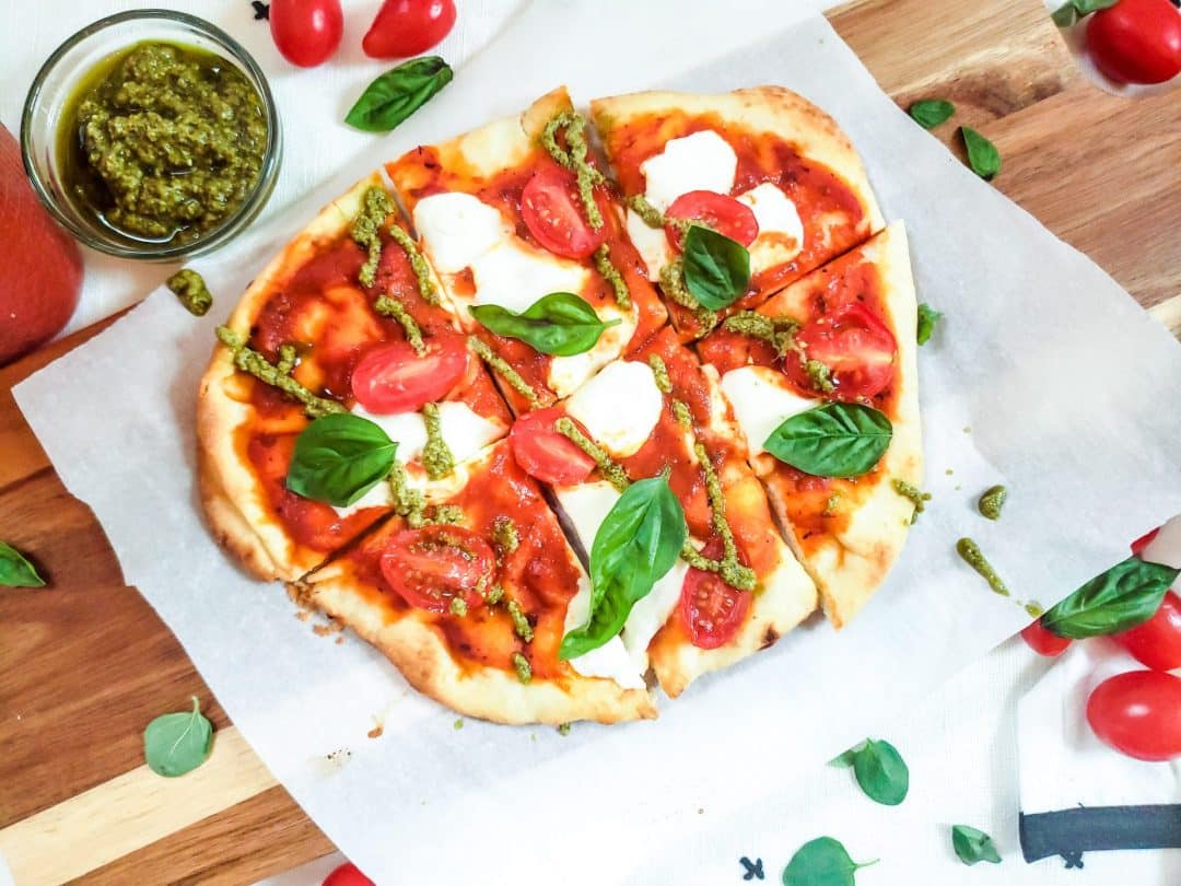 This Easy Margherita Pizza Recipe is easy, fast and vegetarian! This recipe is perfect for families, mine loves having this for dinner! This recipe uses naan bread, mozzarella cheese and basil pesto! #pizzarecipes #flatbread
