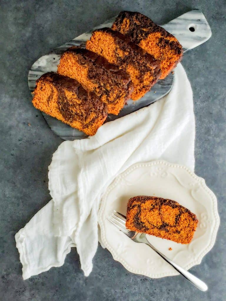 Overhead shot of sliced pumpkin bread on a cutting board and white plate.