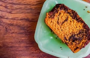 A close up shot of the pumpkin bread on a glass teal plate. The plate is sitting on a wooden surface.