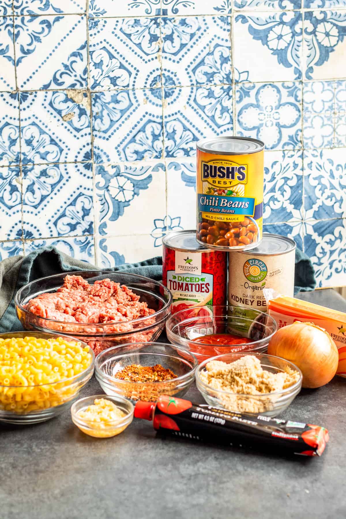 Chili ingredients laid out on table in bowls, containers and plates.