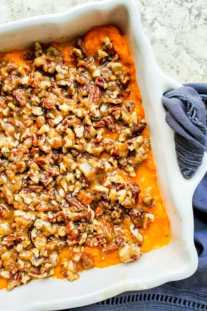 Overhead shot of sweet potato casserole in a white baking dish on a white counter.