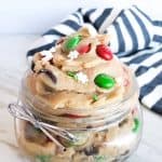 Glass mason jar with cookie dough in it on white counter.