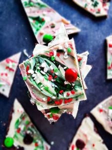 Christmas chocolate bark stacked on top of each other on a blue counter top.