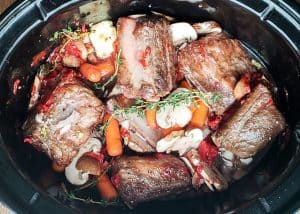 Prep image for crockpot beef short ribs recipe. Image is shot from above and shows all ingredients in a crockpot uncooked.