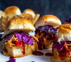 Image for Crockpot Hawaiian BBQ Chicken Sliders. Image is a close up shot of one slider with 2 other blurred out. 