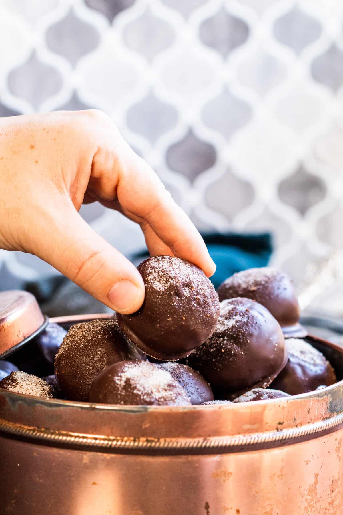 Hand picking up truffle from tin.