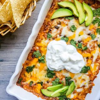 Baked chicken dip in a white baking dish with chips on the side.