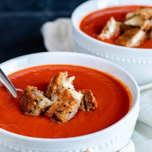 Two white bowls of soup on a blue counter.