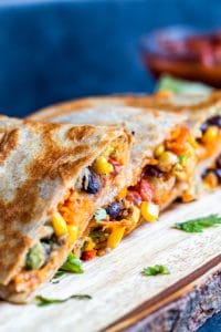 Vegetarian Quesadillas on a wooden cutting board with blue background. 