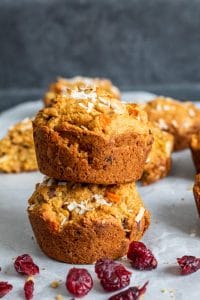 Two Morning glory muffins stacked on top of each other on white parchment paper. 