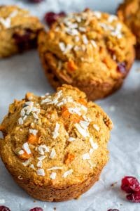 The image shows the muffins on parchment paper. The image is shot from 45 degrees and shows two muffins focused on the tops with some blurred out in the background. 