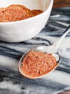 Easy Homemade Taco Seasoning on a silver spoon with more in a white bowl.