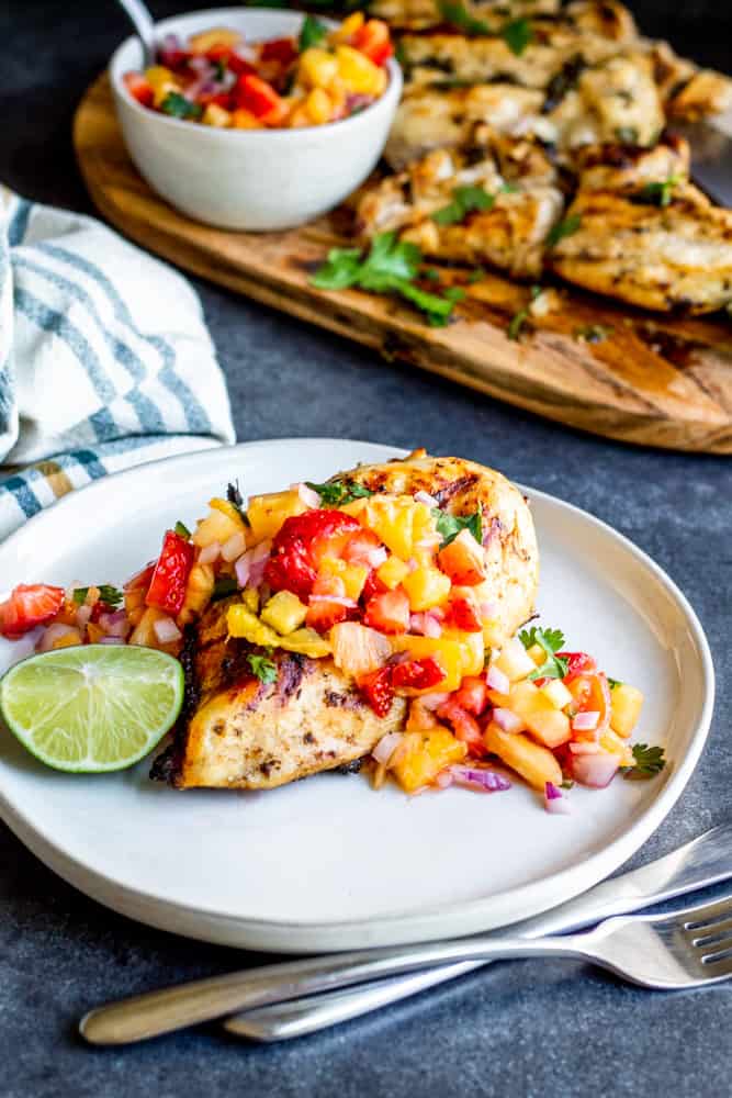 This Cilantro Lime Grilled Chicken recipe is perfect all summer long! Pair with Strawberry Pineapple Salsa for a healthy and fresh combo perfect on its own, with tacos, in burrito bowls, or in a salad! The marinade is simple and fast and can be made ahead of time for easy prep. Give this recipe a try at your next family BBQ, party or 4th of July cookout. #healthy #ChickenRecipes #BBQ #Salsa #glutenfree