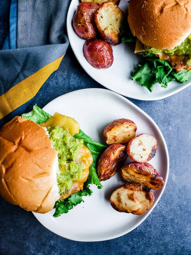 Overhead shot of two chicken burgers on white plates.