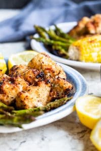 Grilled chicken on blue plate with veggies and lemons. 