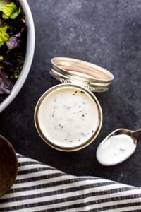 Overhead shot showing ranch dressing in mason jar with salad in a bowl out of frame.