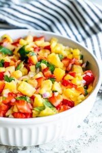 Salsa in a white bowl with a blue and white striped towel in background. 