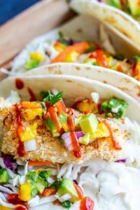 Close up of fish taco on a tortilla with mango salsa on top.