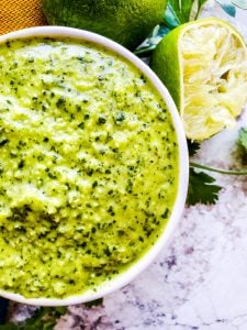 Close up overhead shot of sauce in a white bowl with lime next to it.