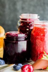 Strait on shot of three jams in glass containers with gray background.