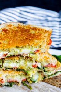 Angle shot of grilled cheese stacked on top of each other on top of a wood and white marble cutting board.