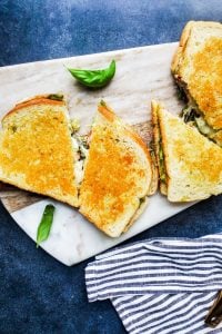 Overhead shot of two grilled cheese sandwiches on a cutting board sliced in half. 