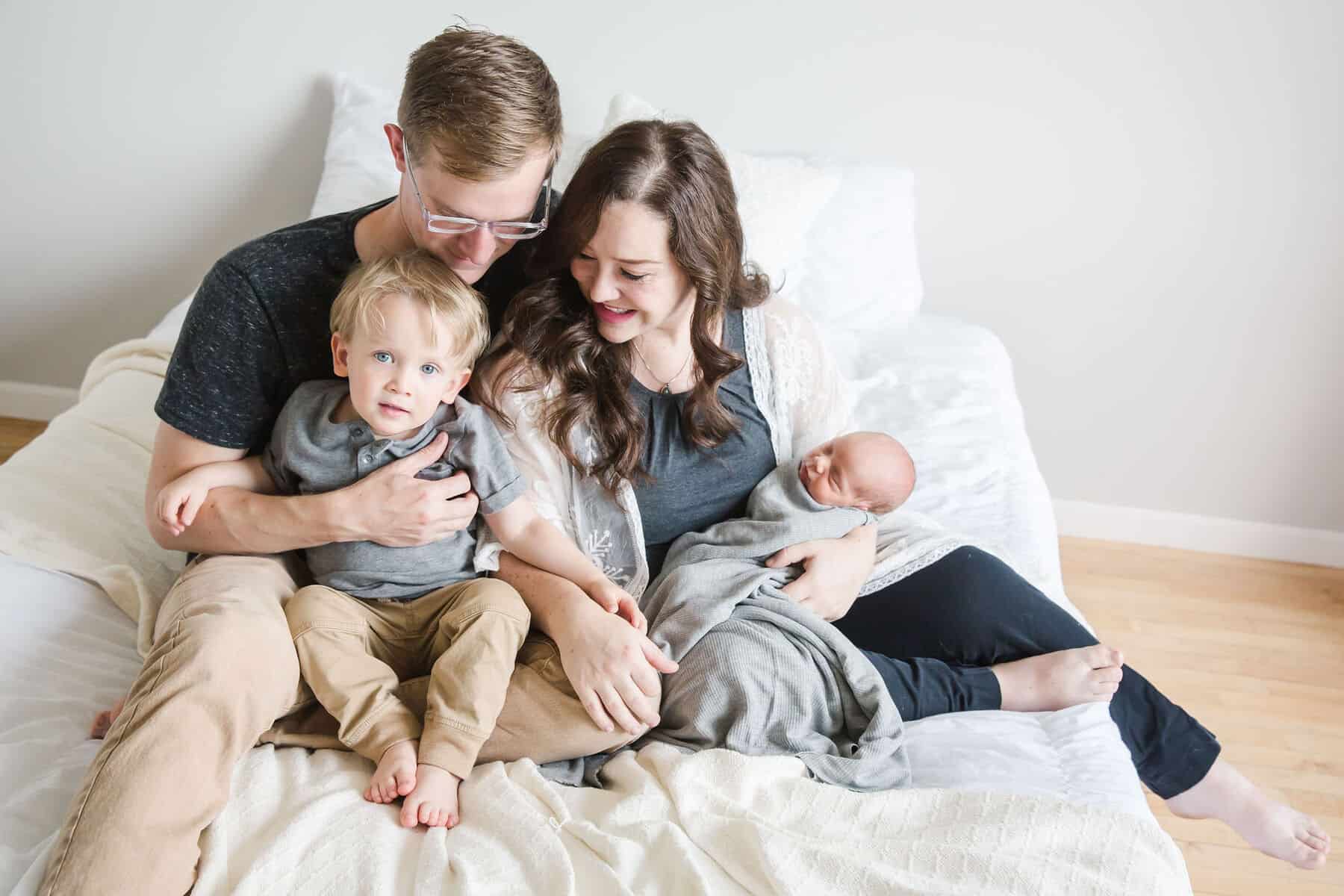 Family photo sitting on a white bed with white background.