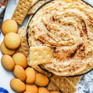 Overhead shot of pumpkin dip in a black bowl on a white counter.