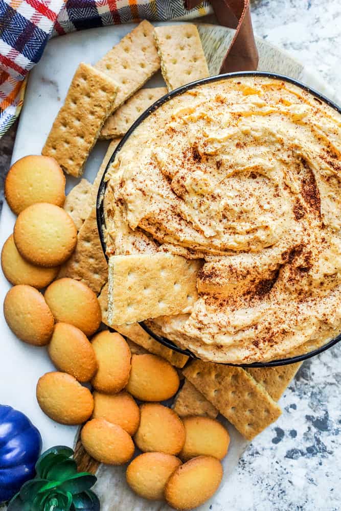 Overhead shot of pumpkin dip in a black bowl on a white counter.