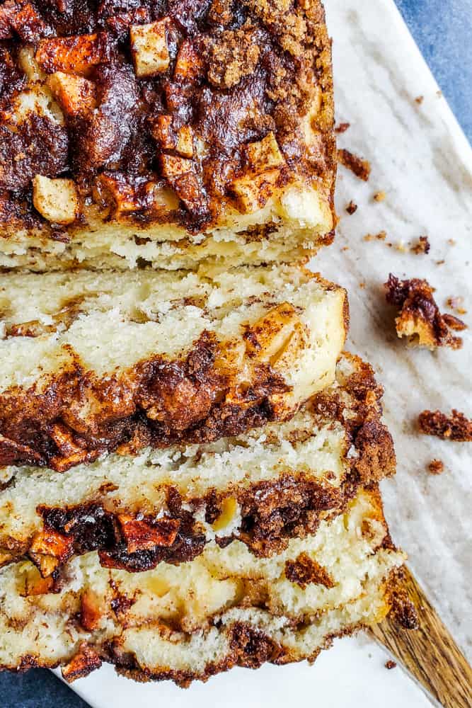 Slices of apple cinnamon bread on a white marble cutting board.