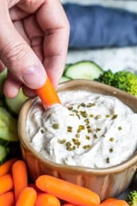 Hand dipping a carrot into dip.