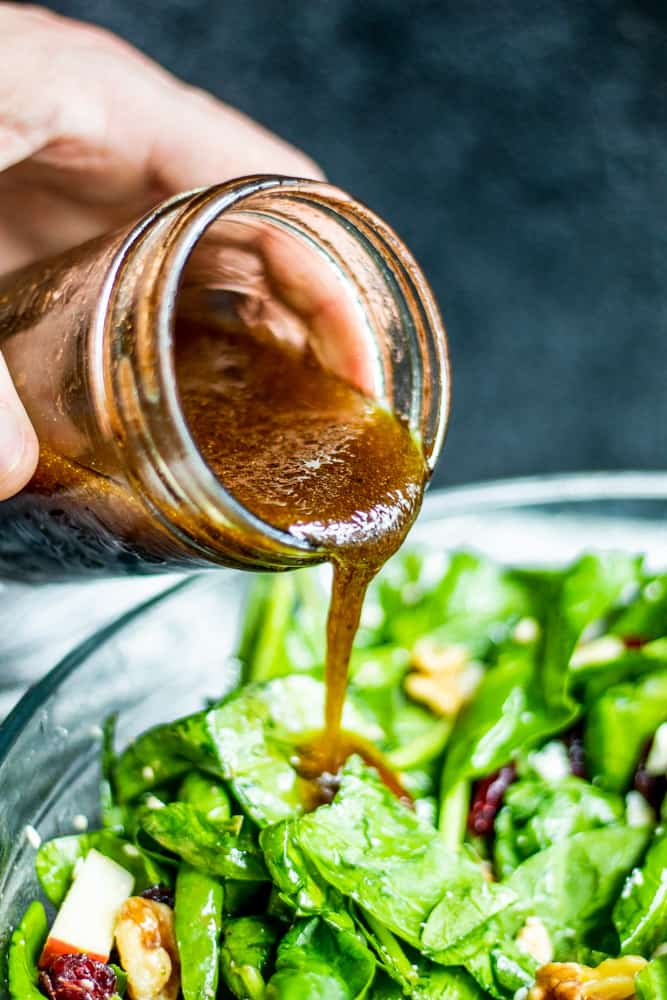 Homemade Balsamic Dressing being poured over salad in a glass bowl.