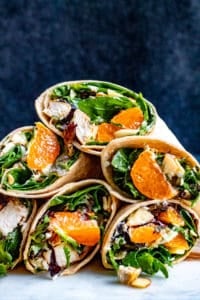 Stacks of chicken wraps on a white counter with blue background.