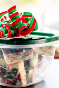 Sugar Cookie Fudge in a container with a green lid and red and green bow on top.