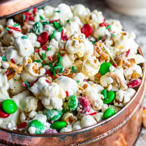 Popcorn snack mix in a copper tin on a white counter.