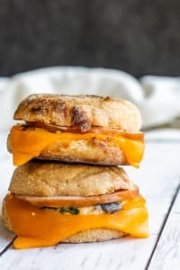 Two make ahead breakfast sandwiches stacked on top of each other on a white counter.