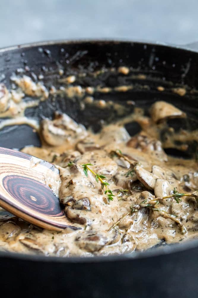 Sauce in a black skillet with a wooden spoon dipped in.