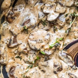Mushroom sauce in a black iron skillet with a wooden spoon.