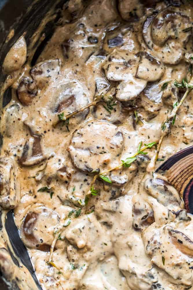 Overhead shot of mushroom sauce in a black skillet with a wooden spoon in it.