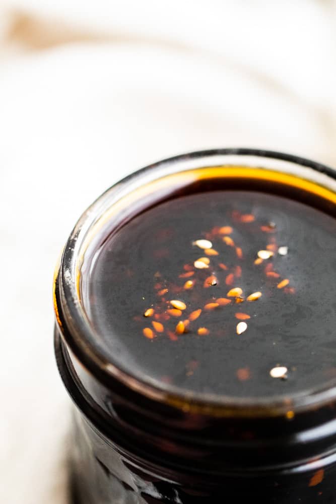 Close up shot of teriyaki sauce in a mason jar with white background.