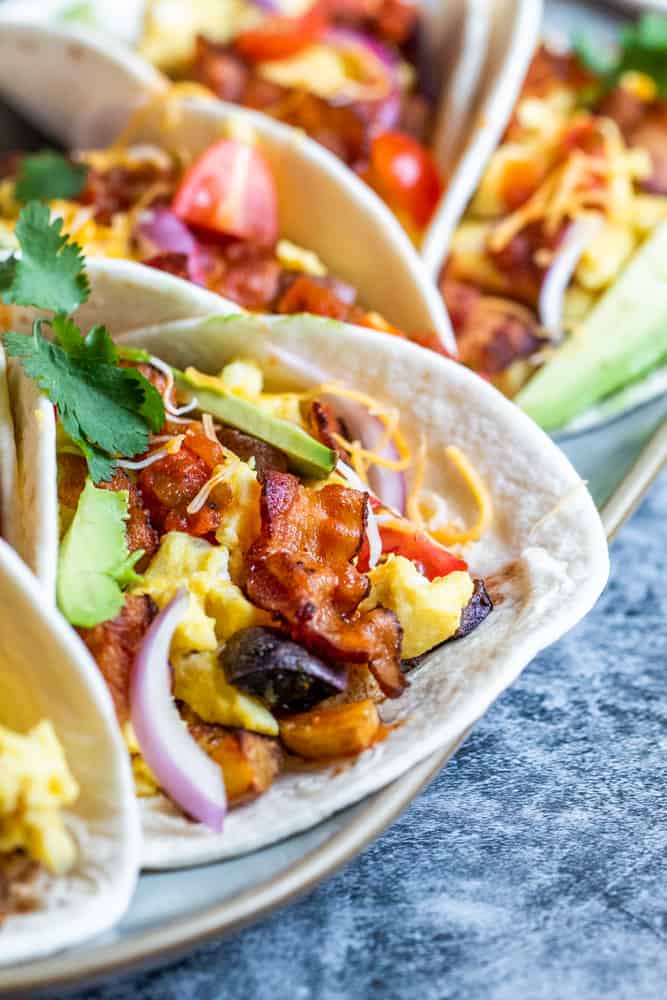 Close up shot of breakfast taco on a white platter on a blue counter.